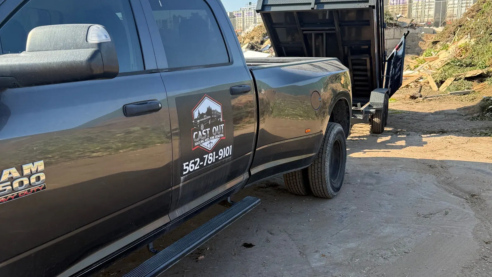 Cast Out pickup with the logo on the door and the dump trailer tipped up behind it at the dump