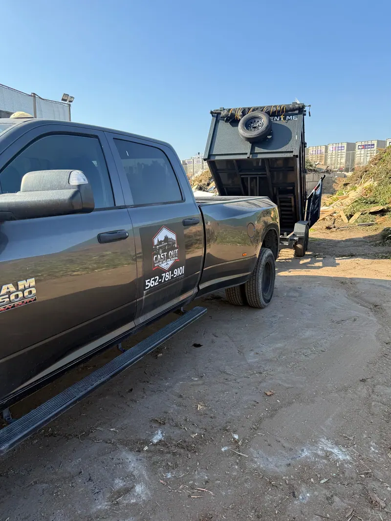 Cast Out pickup with the logo on the door and the dump trailer tipped up behind it at the dump