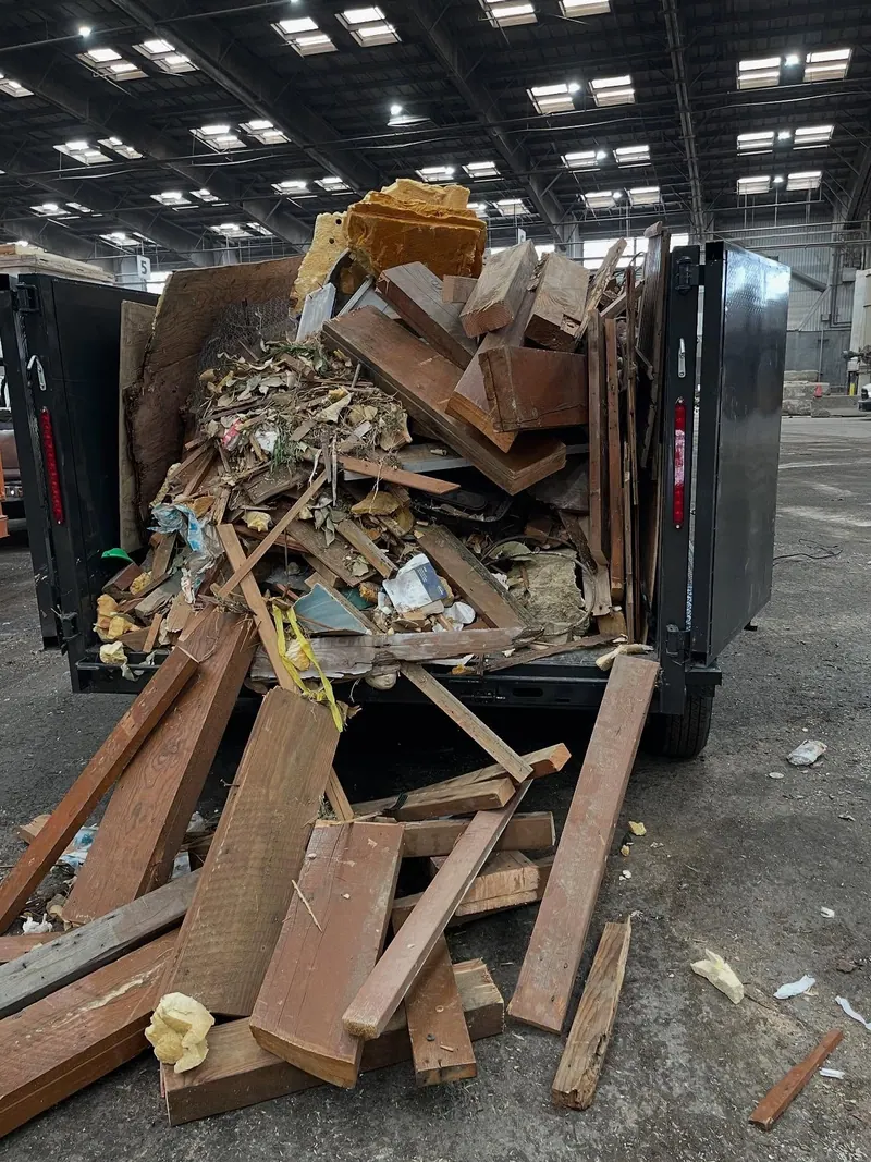 Cast Out dump trailer piled high with broken lumber and remodel debris
