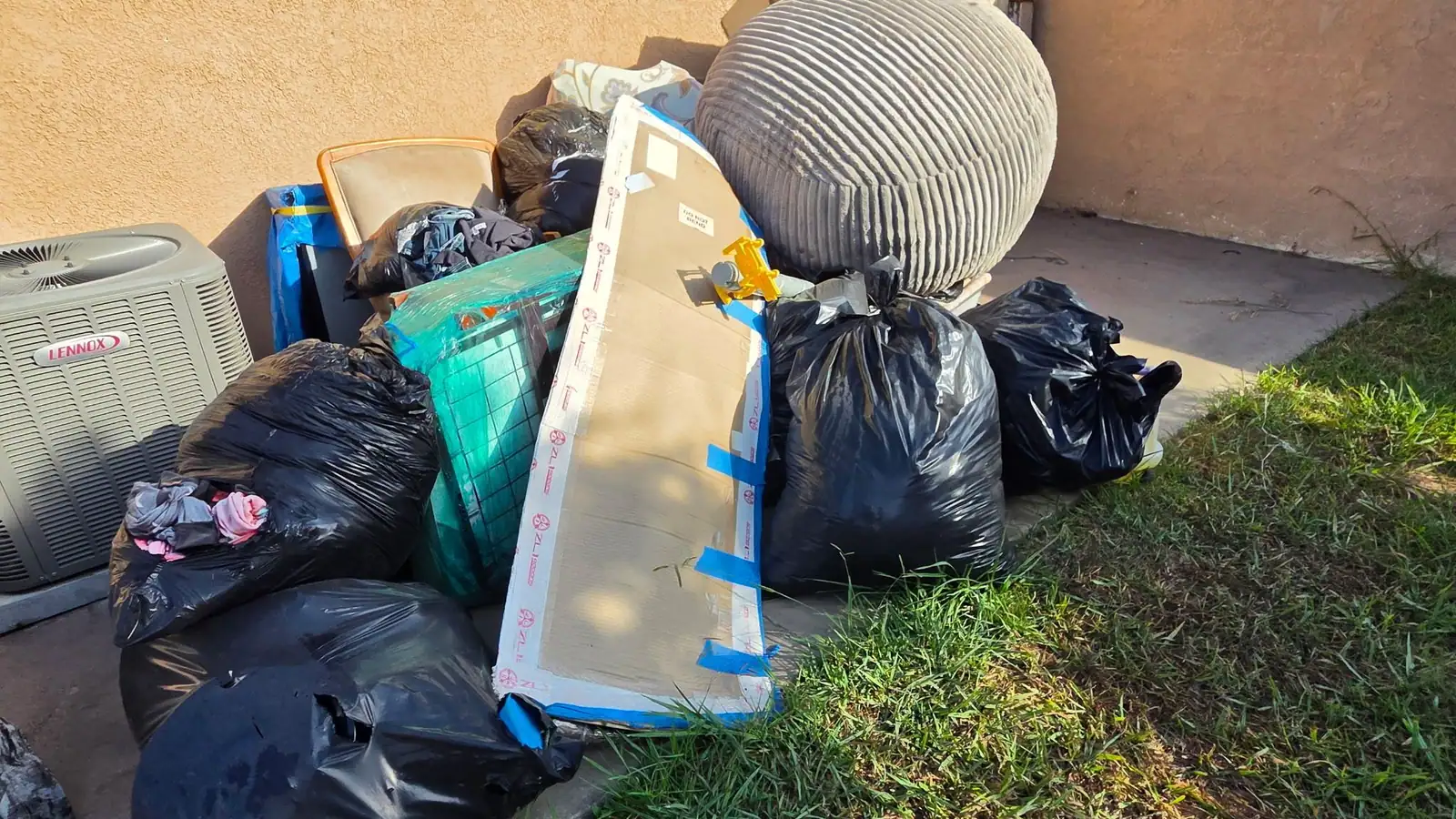 Bagged household junk, a bean bag and an old chair piled on a back patio for pickup