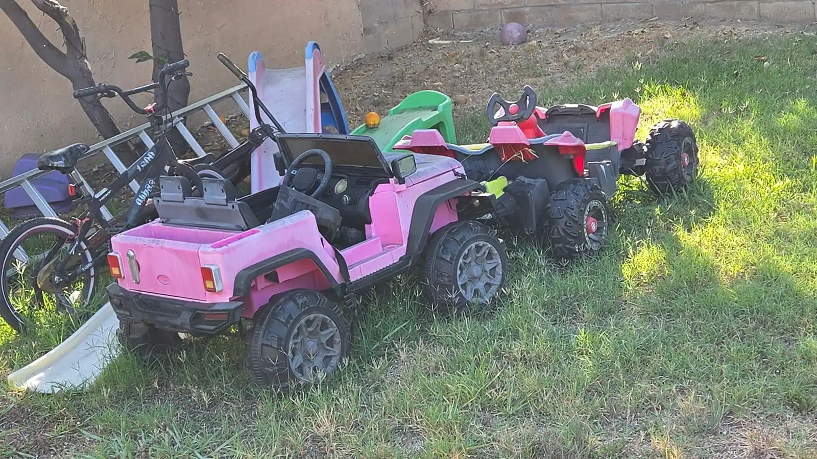 Outgrown kids' ride-on cars and toys gathered on a lawn for pickup