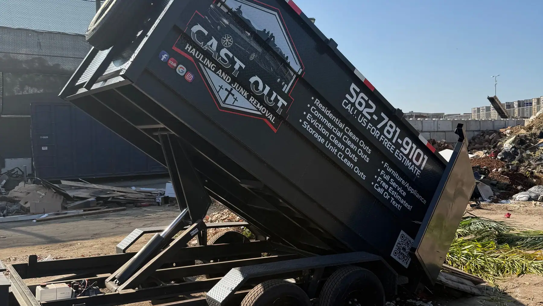 Cast Out dump trailer raised on its hydraulic lift and emptying a load at the dump