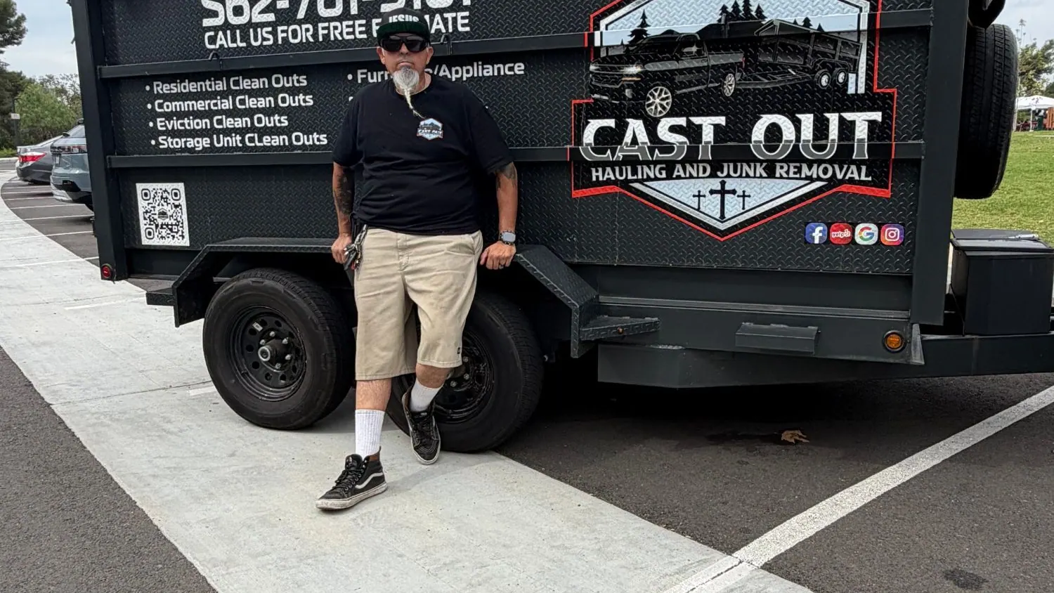 Louie leaning on the Cast Out dump trailer in a parking lot