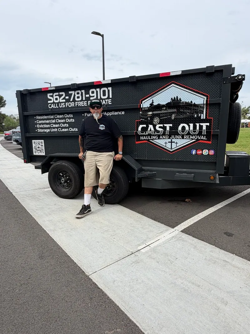 Louie leaning on the Cast Out dump trailer in a parking lot