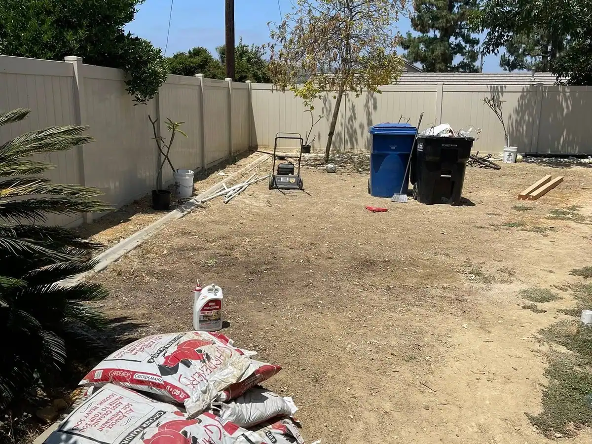 The same backyard cleared to the dirt with only the trash bins left