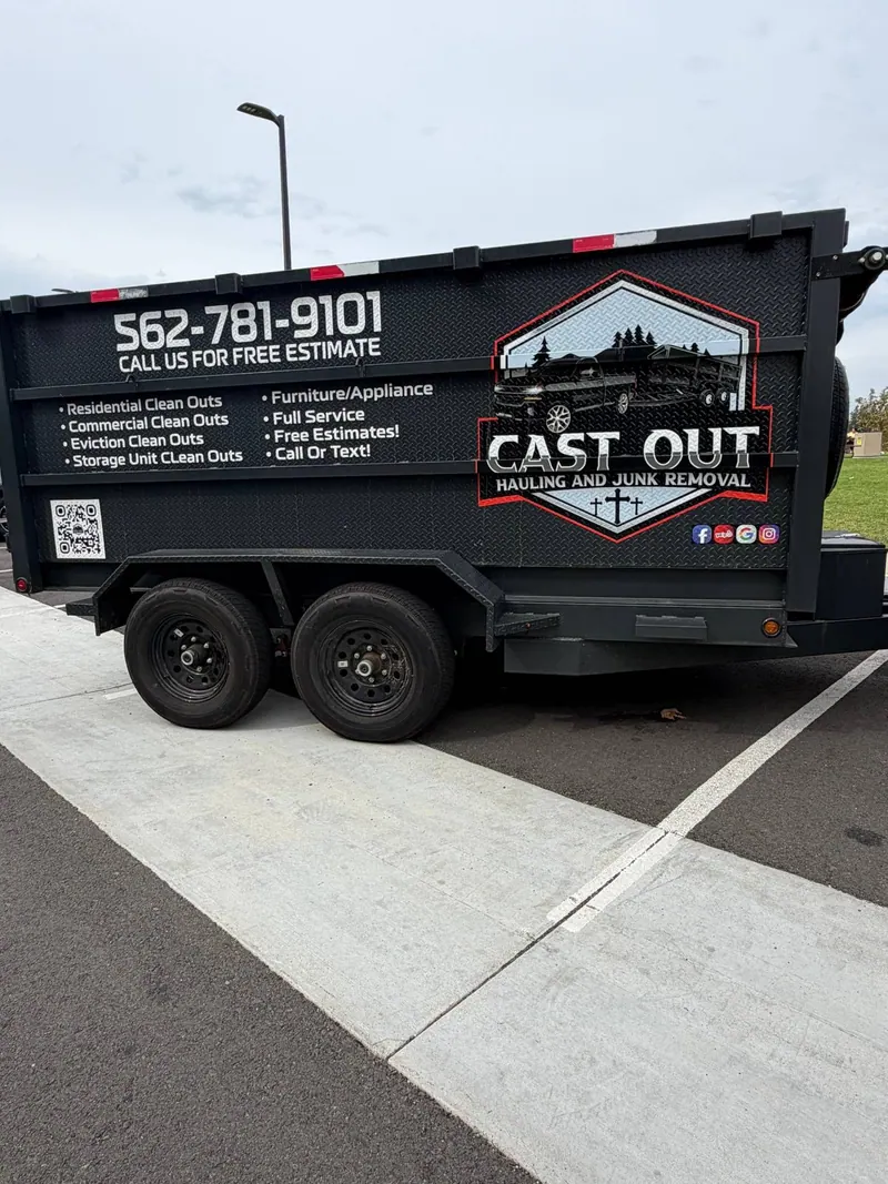 Side of the Cast Out hydraulic dump trailer with the logo, the phone number and the list of cleanouts
