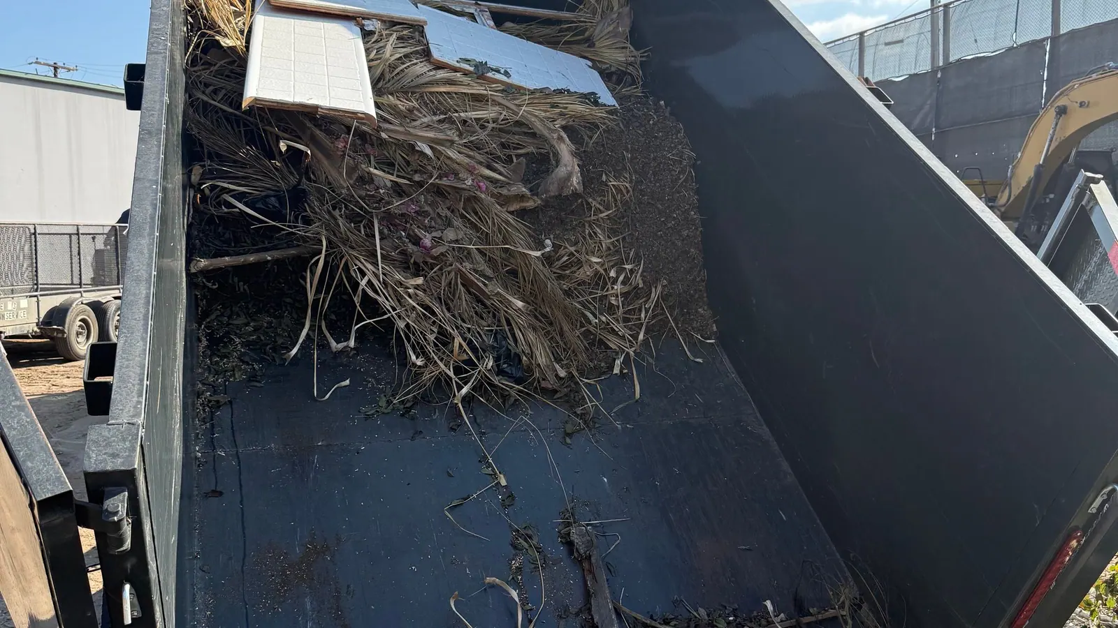 Branches and broken wood sliding out of the tipped Cast Out dump trailer